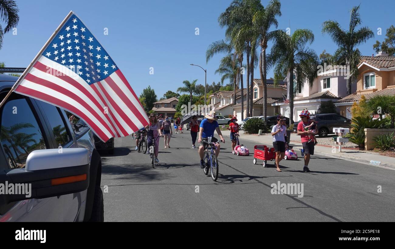 Families participate in a small neighborhood parade celebrating July 4th Stock Photo