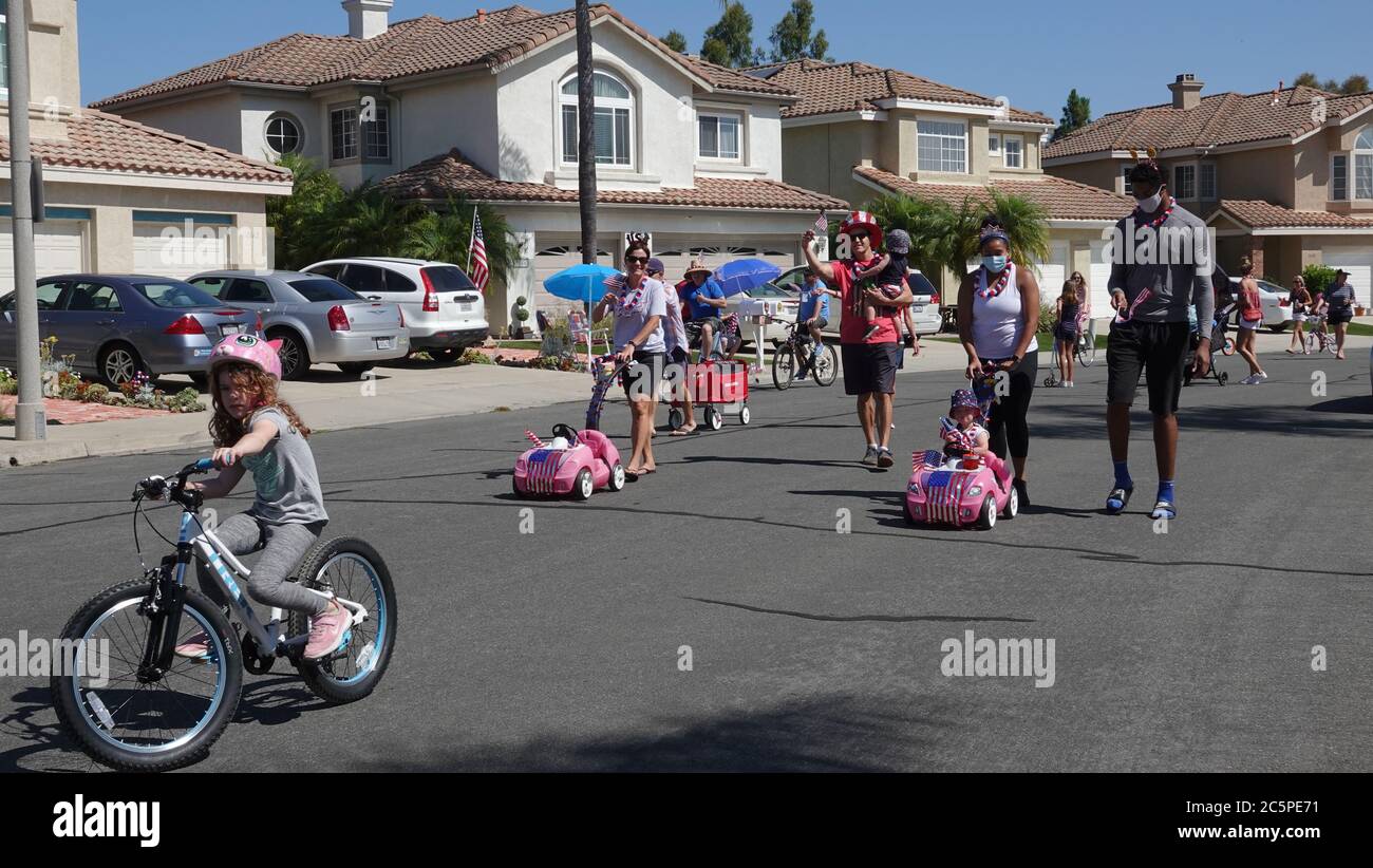 Families participate in a small neighborhood parade celebrating July 4th Stock Photo
