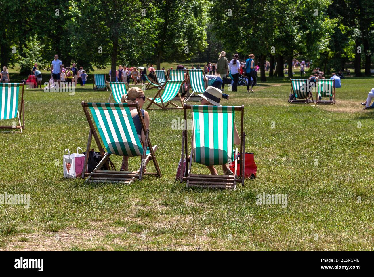 Scattered loungers and people on a park grassy field, London, England, UK. Stock Photo