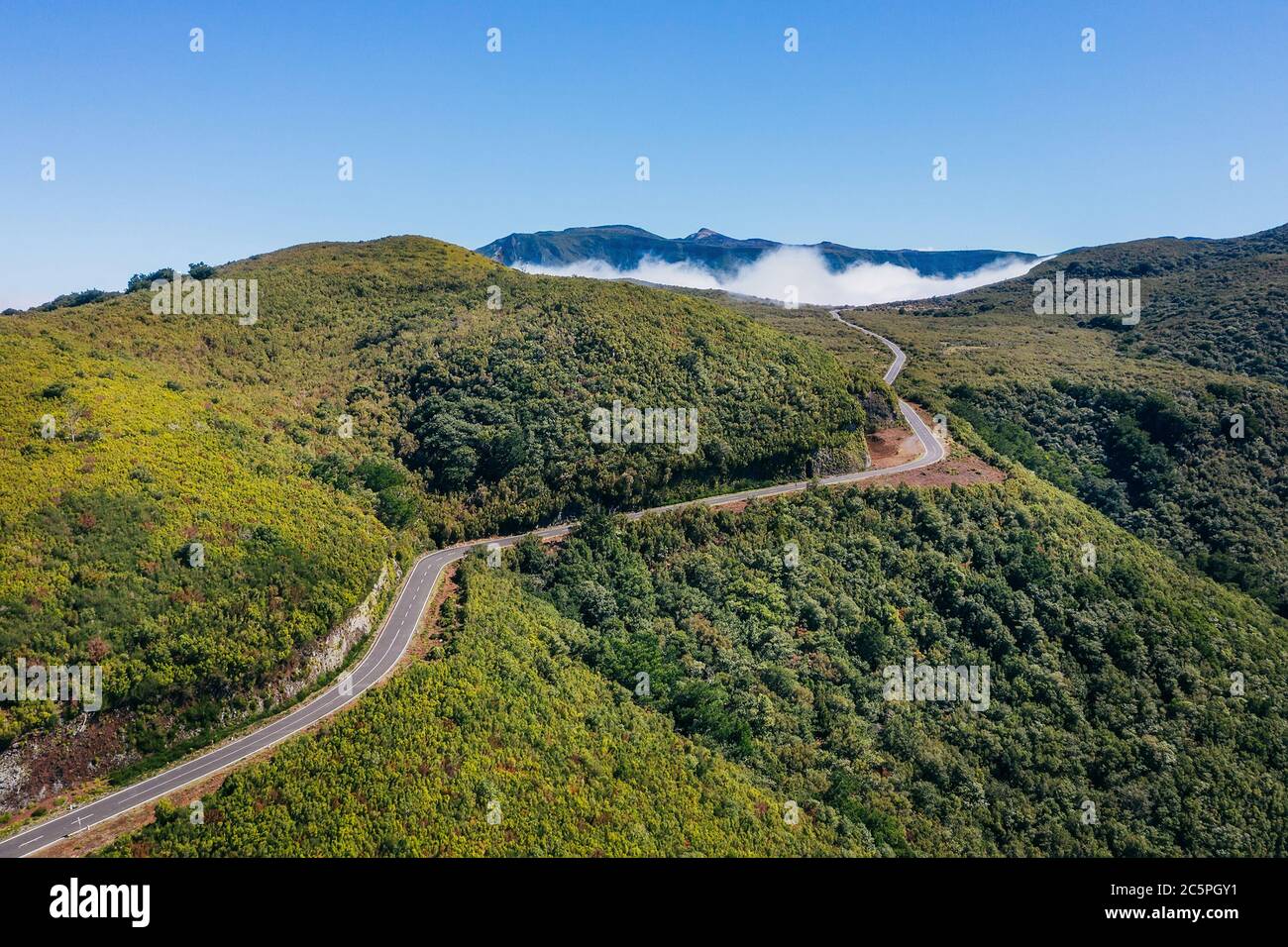 Country asphalt road ER209 leading to clouds stuck at mountain hills in the inland of Madeira island, Portugal aerial drone shot. Traveling and transp Stock Photo