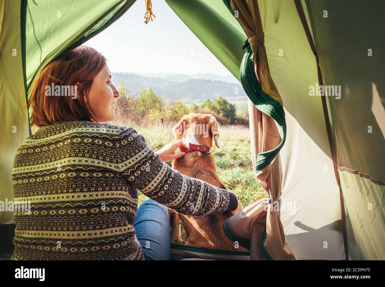 Woman with her pet beagle dog resting in camping tent	. People in outdoor concept image. Stock Photo