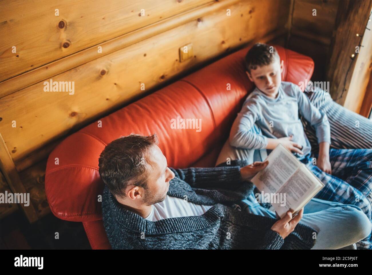 Father reading book to son in cozy country house on a Global Coronavirus COVID-19 pandemic Outbreak days. World 2019–20 coronavirus pandemic, home edu Stock Photo