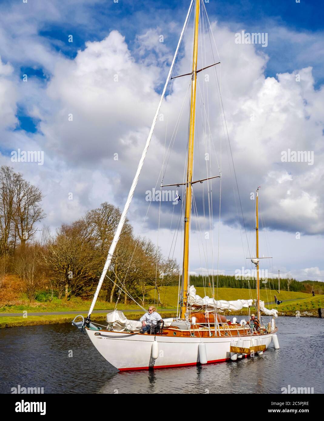 Sailing yacht with couple on board going through water lock on Crinan Canal, Argyll, Scotland, UK Stock Photo