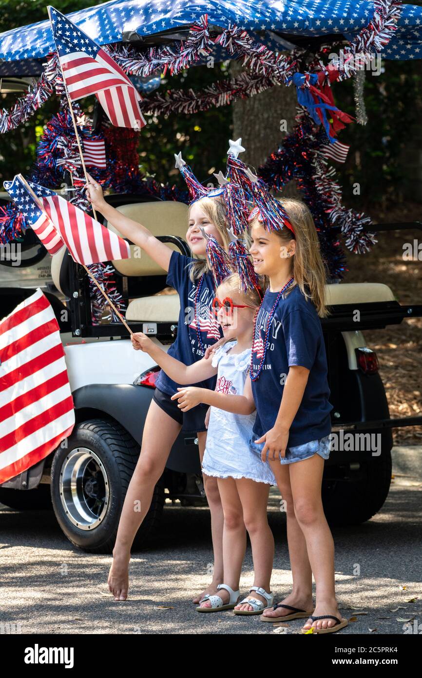 Mount Pleasant, United States of America. 04 July, 2020. Children wave flags during an Independence Day parade despite a dramatic rise in COVID-19, coronavirus cases in Charleston County July 4, 2020 in Mount Pleasant, South Carolina. South Carolina is currently number three nationwide in number of infected per population. Credit: Richard Ellis/Alamy Live News Stock Photo
