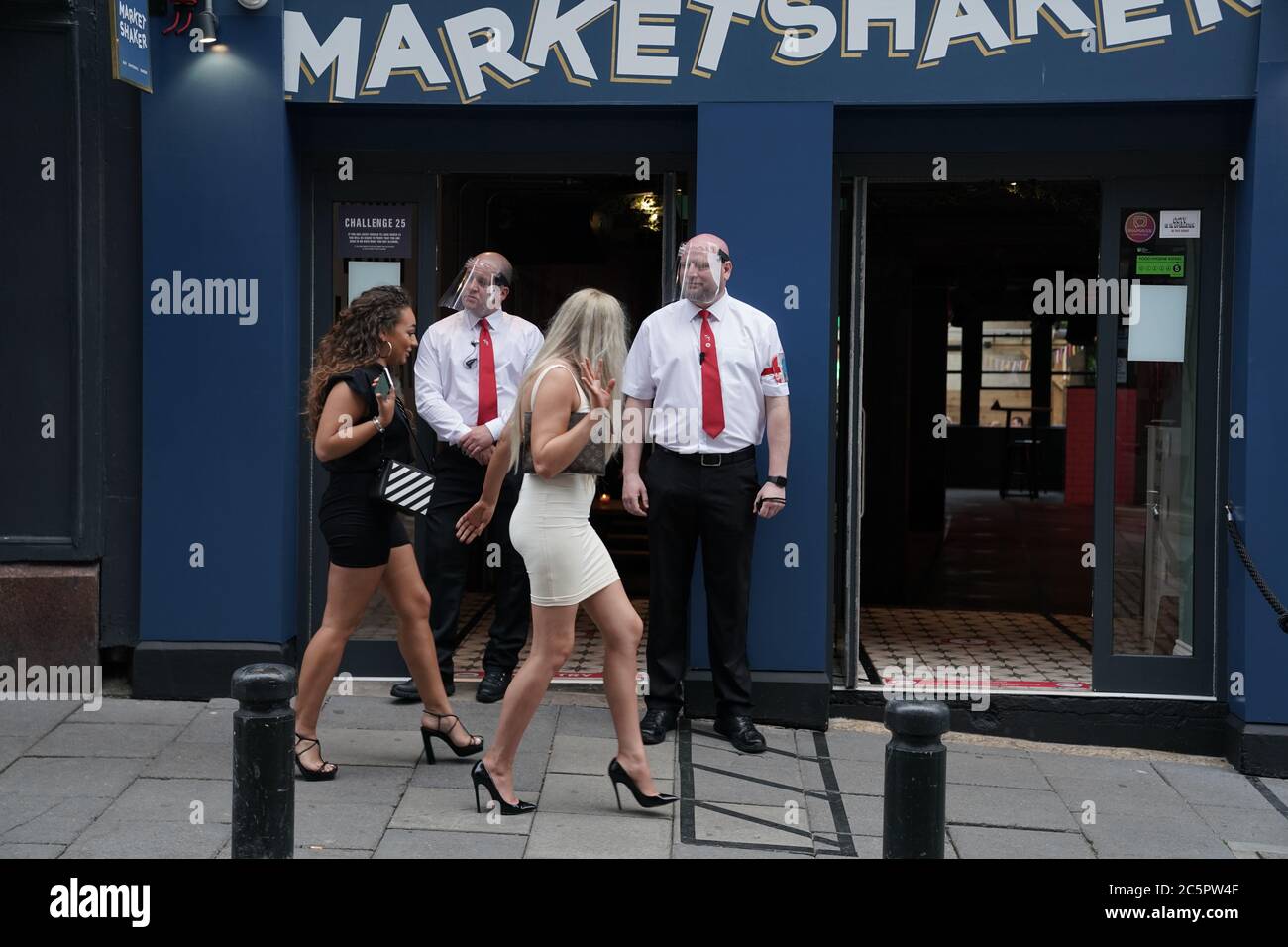 Door staff in PPE and people outside Market Shaker in the Bigg Market area of Newcastle, where pubs and bars have reopened following the easing of coronavirus lockdown restrictions across England. Stock Photo
