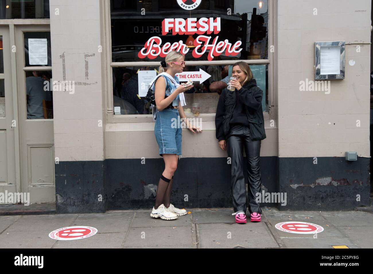 Social Distancing UK pubs London 4th July 2020. Super Saturday, bars and pubs open with restrictions in place, social distancing. Portobello Road young Londoners. Teen girls having a pint. The circles on the pavement are 6 feet apart. 2020s UK HOMER SYKES Stock Photo