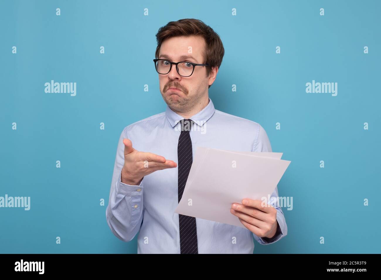 Satisfied young man with glasses checking documentation. Stock Photo