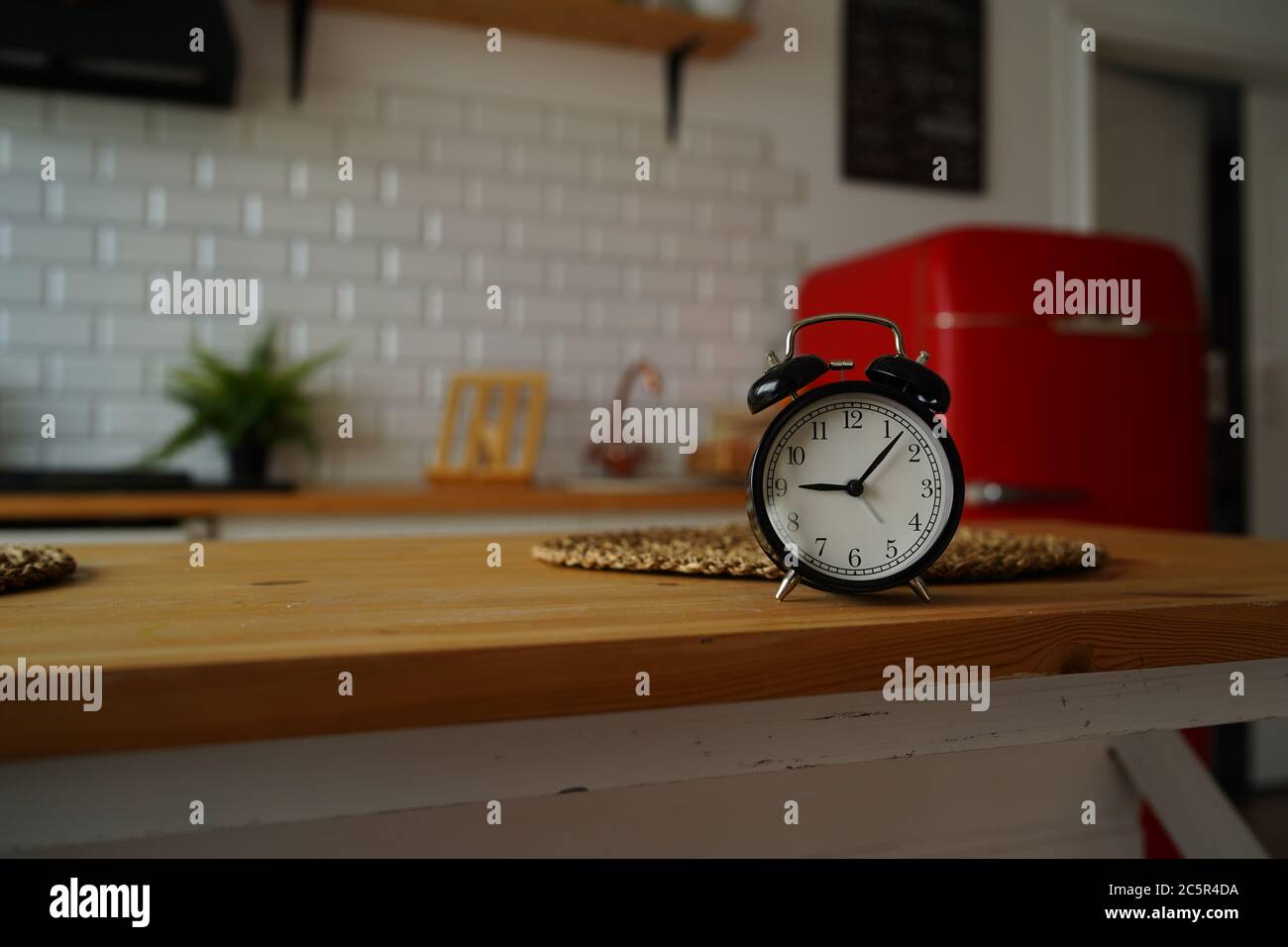 Close up of alarm clock on table in kitchen. Black vintage clock on kitchen table. Stock Photo
