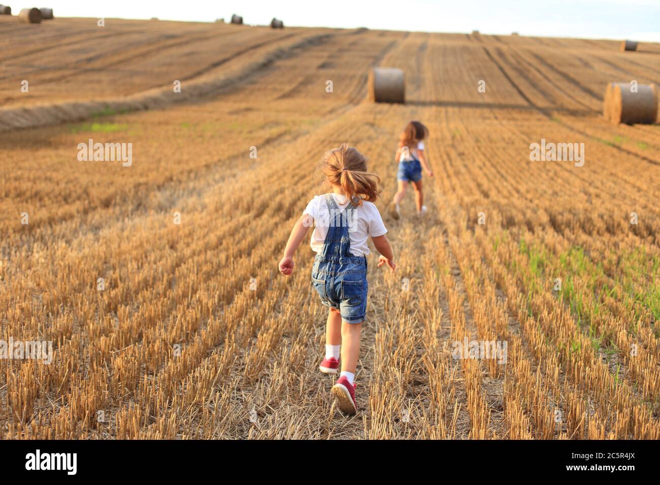 Girlfriends run on a sloping field in summer Stock Photo