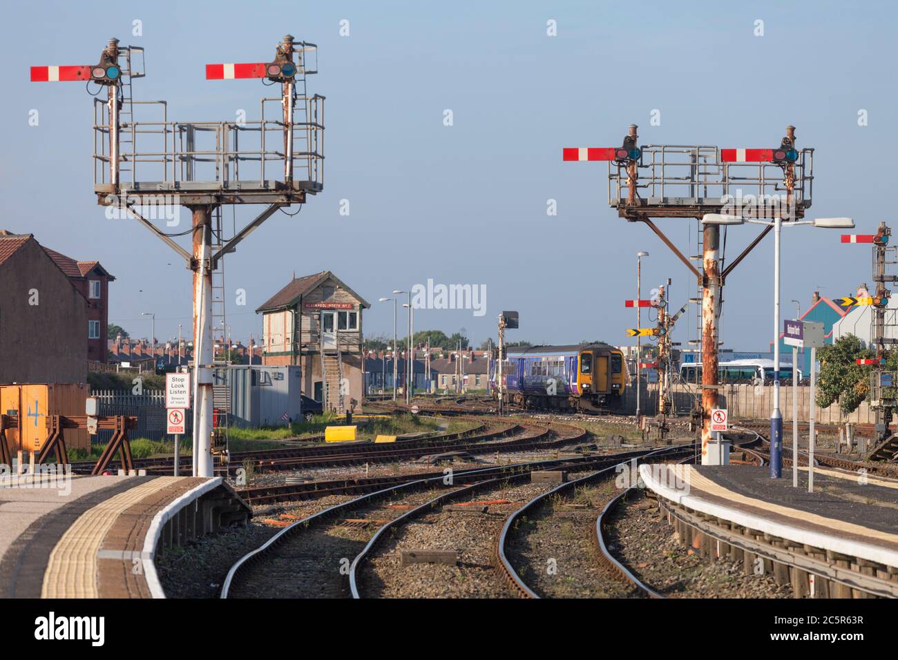 Northern Rail class 156 sprinter train arriving at Blackpool North railway station with the mechanical semaphore home and distant railway signals Stock Photo