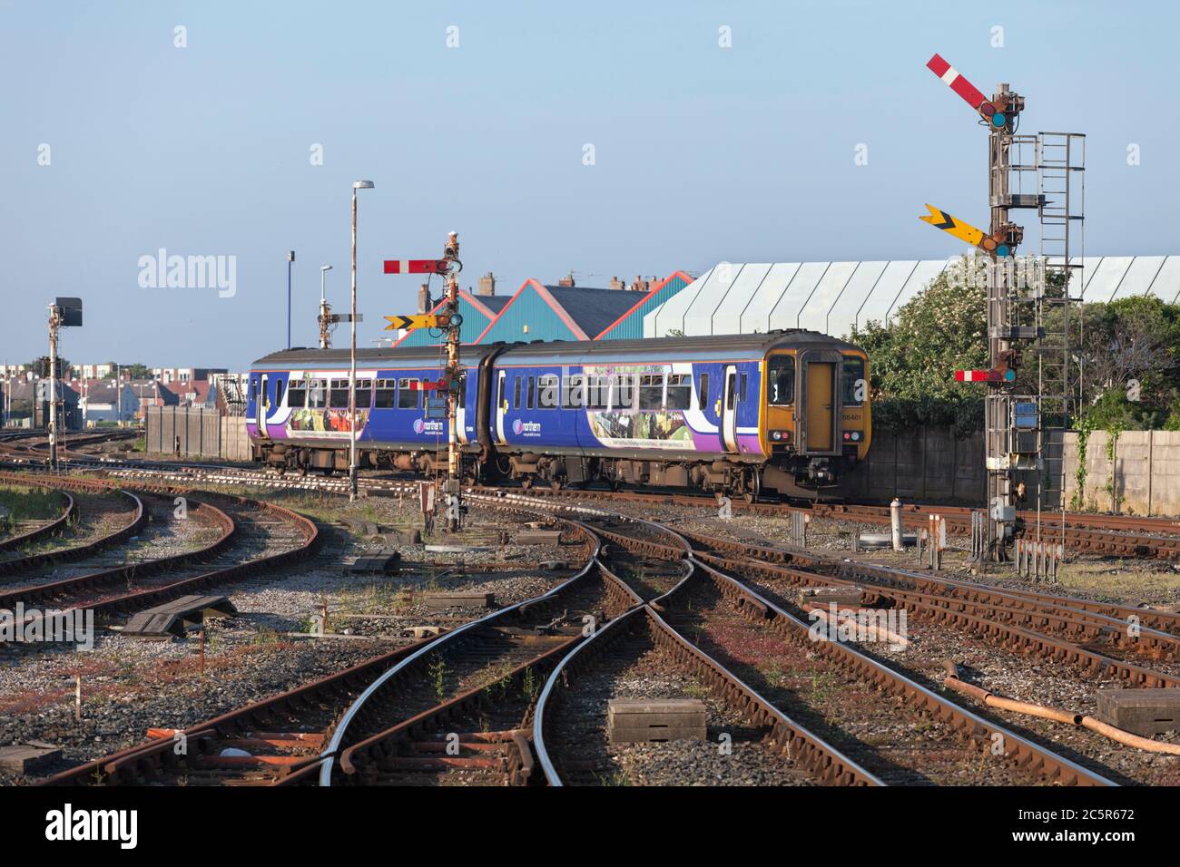 Northern Rail class 156 sprinter train departing Blackpool North railway station with the mechanical semaphore home and distant railway signals Stock Photo