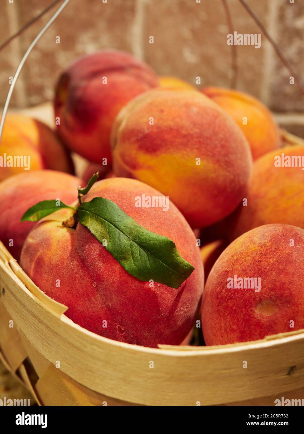 Fresh, ripe cling free peaches a summer fruit in a basket on a kitchen countertop. Stock Photo