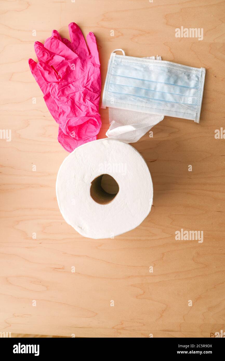 A roll of toilet paper pink disposable gloves and a disposable mask for