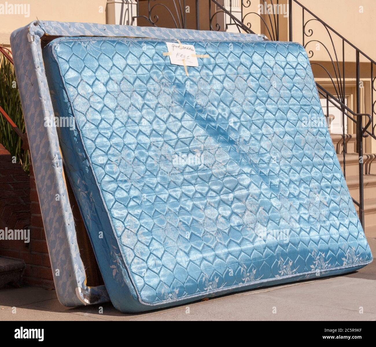 Relatively clean mattress and box spring discarded outside urban apartment building. Free to good home. Stock Photo
