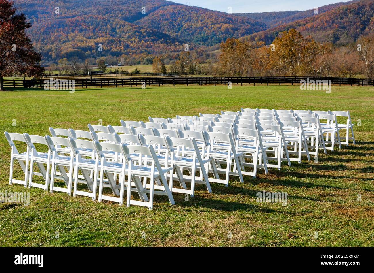 Beautiful Virginia autumn wedding setting at the foot of the Blue Ridge Mountains. Rows of precisely spaced white chairs. Stock Photo
