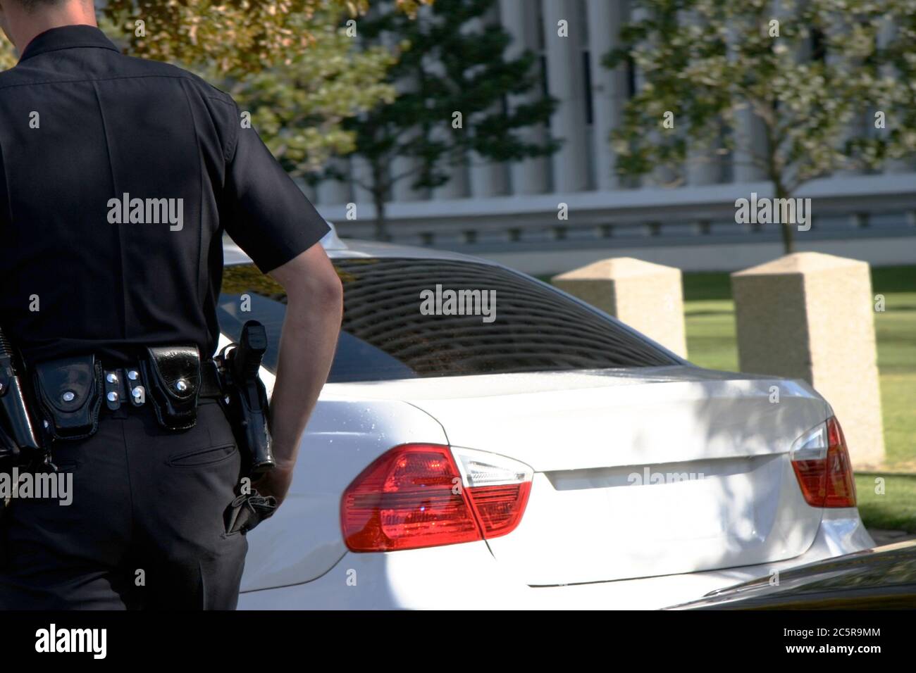 Rear view of traffic officer cautiously approaching stopped vehicle. Horizontal. Stock Photo