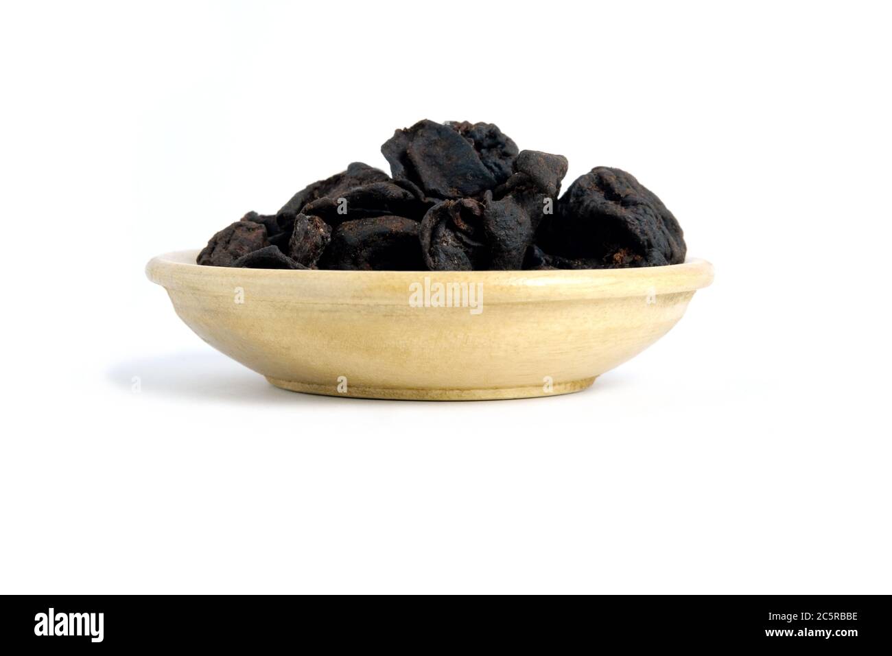 Closeup garcinia cochinchinensis (called Asam kandis in Indonesia) on wooden plate isolated white background with studio lighting Stock Photo