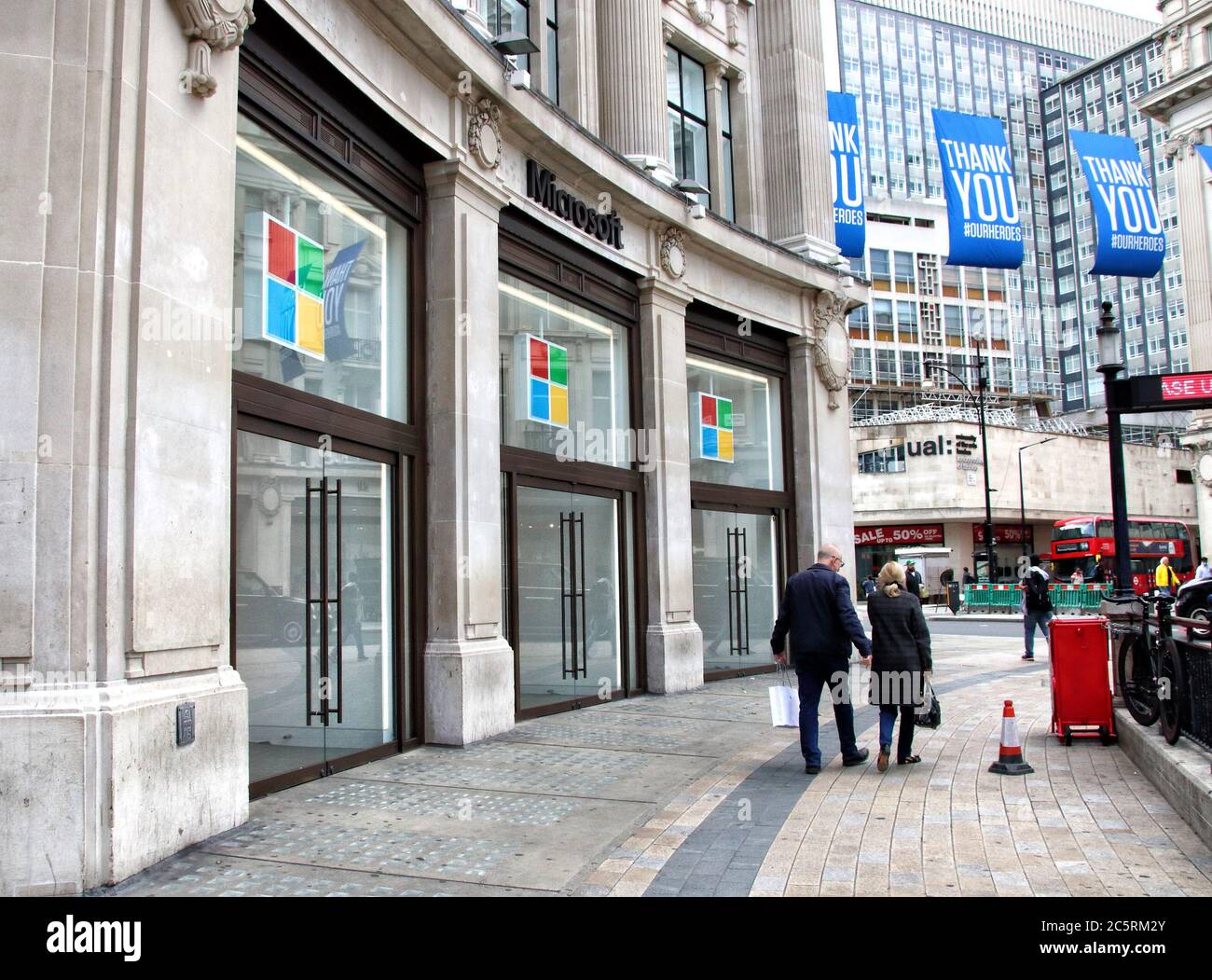 London, UK. 03rd July, 2020. A couple walk past the Microsoft store.Microsoft has said it will keep all of its retail locations closed permanently, including London's Flagship store in Oxford Circus which opened just one year ago. The company says it will reimagine some of its spaces that serve its customers, including the Microsoft Experience Centre in London. Credit: SOPA Images Limited/Alamy Live News Stock Photo