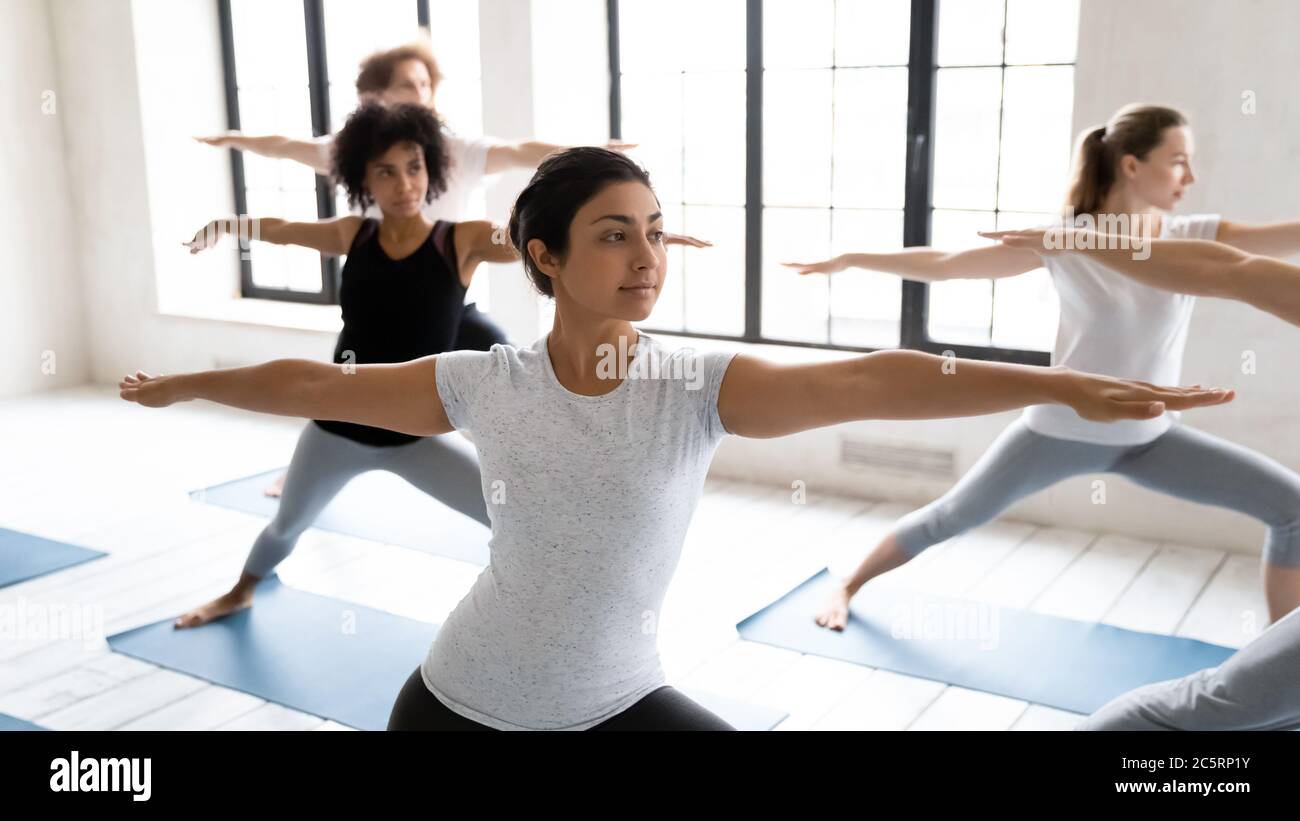 Young fit indian ethnicity woman standing in virabhadrasana second position. Stock Photo