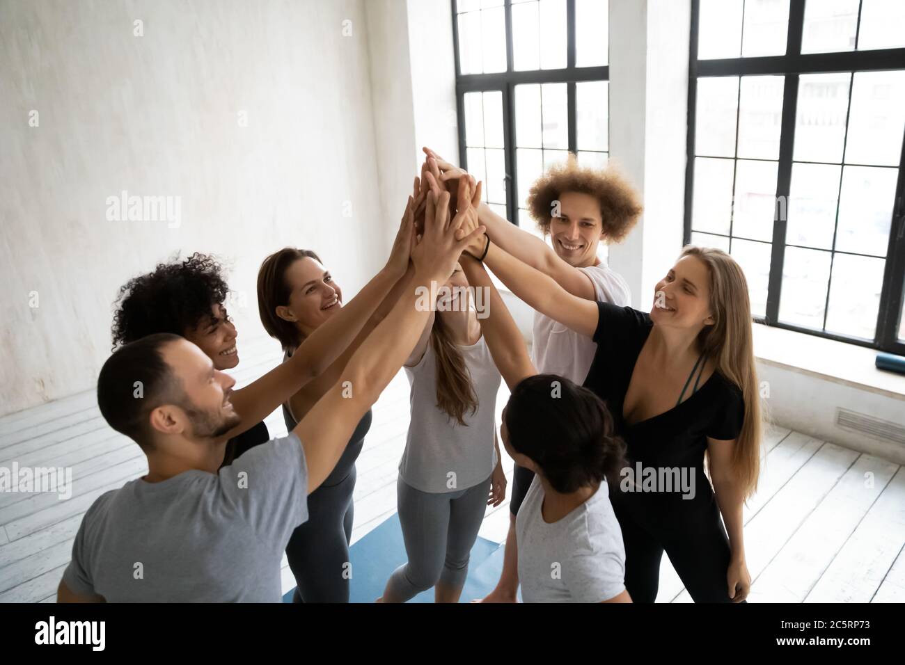 Young multiracial people in activewear giving high five after training ...
