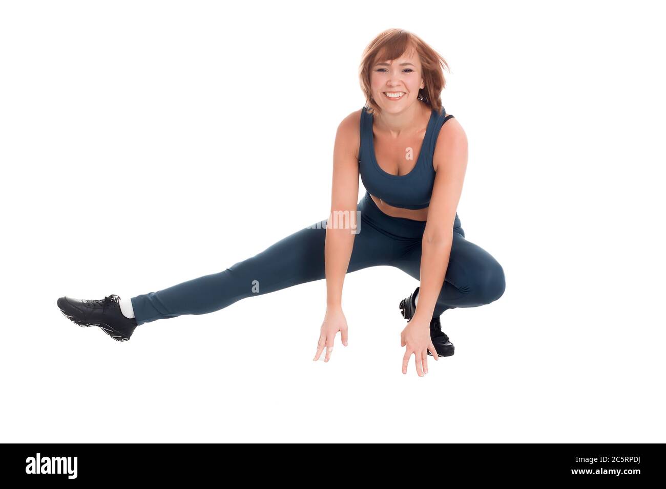 Healthy fitness middle-aged Asian woman in classic blue sportswear, squats on one leg on a white background of isolate Stock Photo