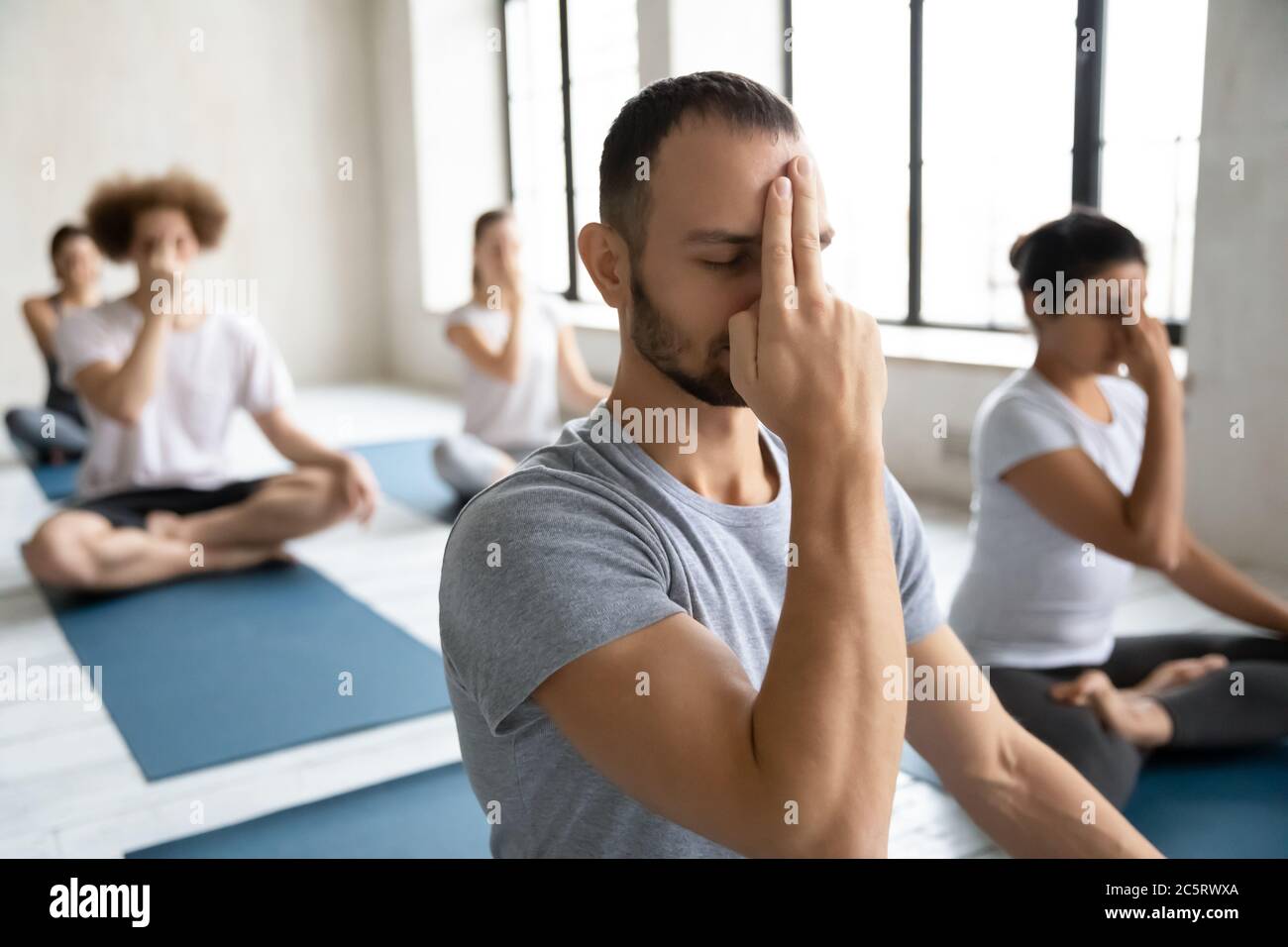 Young Mindful Male Trainer Showing Alternate Nostril Breathing To