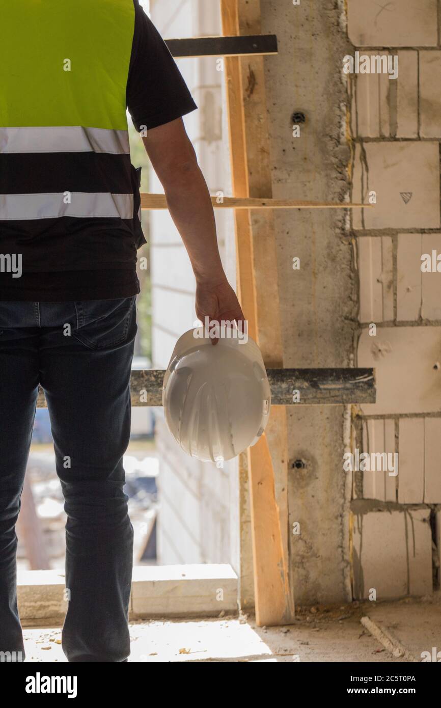 Builder holding helmet on hand, construction site Stock Photo
