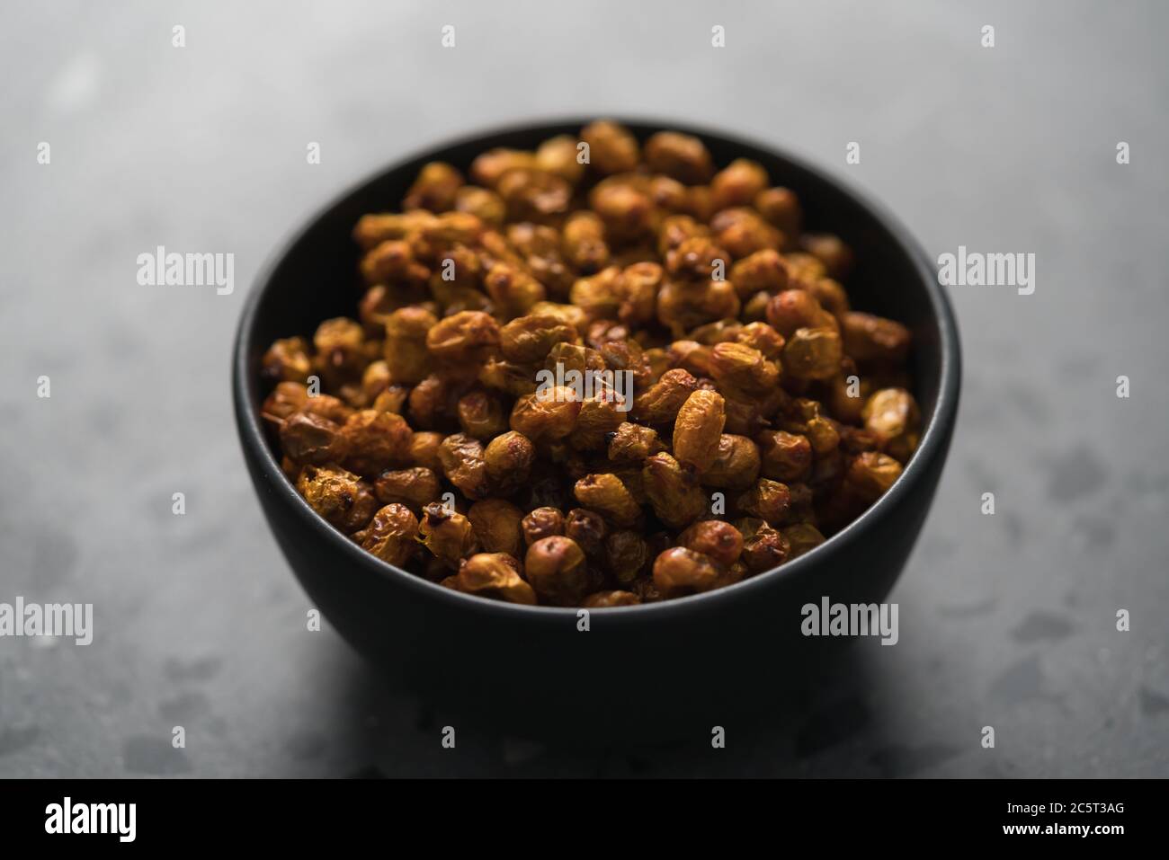 dried seaberry buckthorn in black bowl on terrazzo countertop Stock Photo