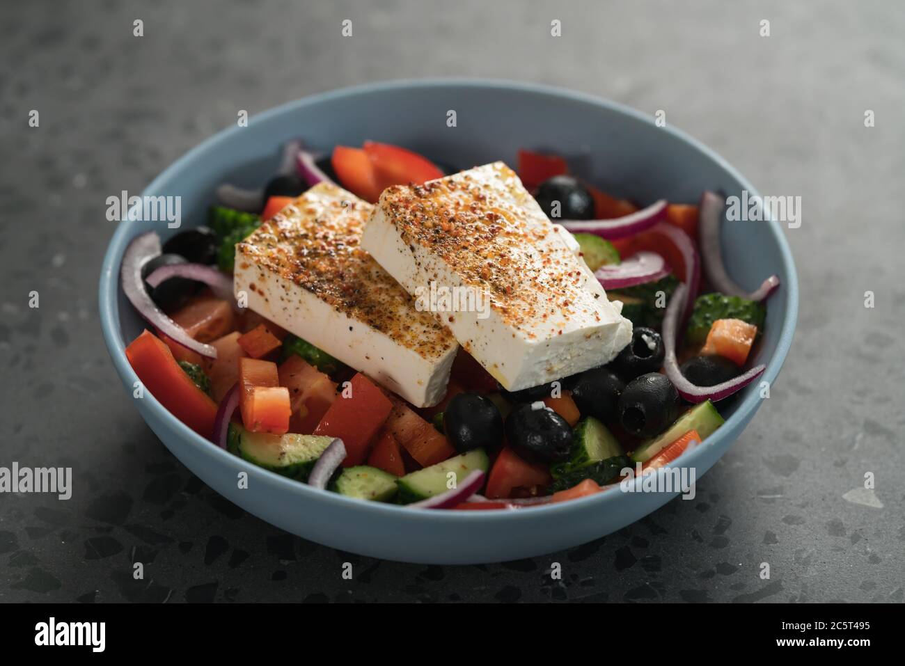 Traditional greek salad in blue bowl on concrete background Stock Photo