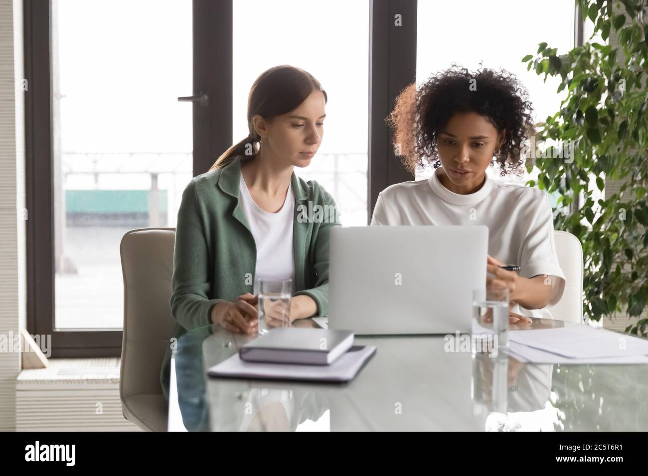 Young multiracial female colleagues work on laptop in office Stock ...