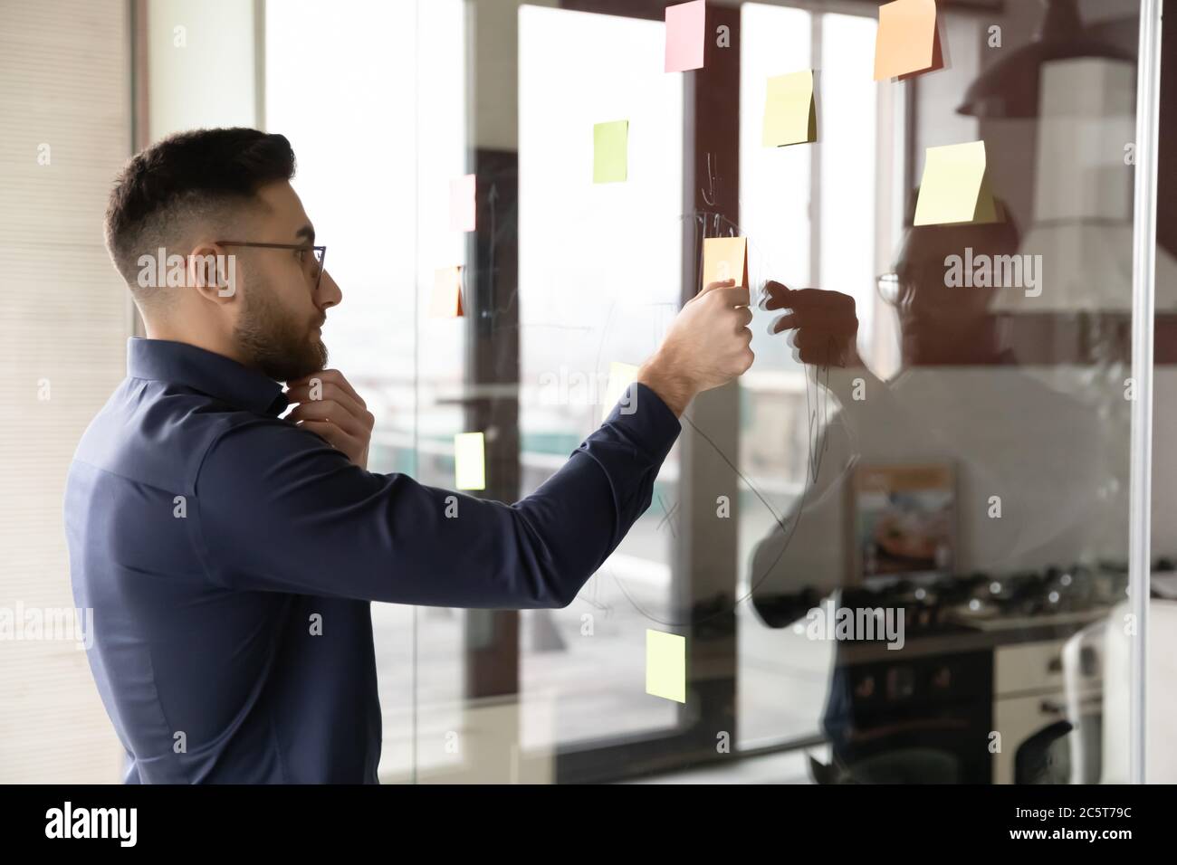 Pensive Arabic businessman develop business plan on wall Stock Photo