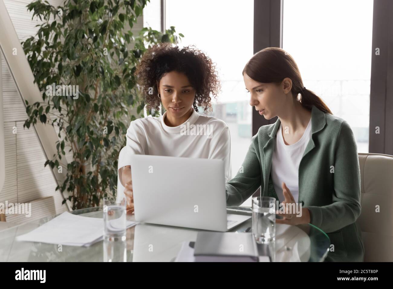 Multiracial female employees cooperate using computer in office Stock Photo