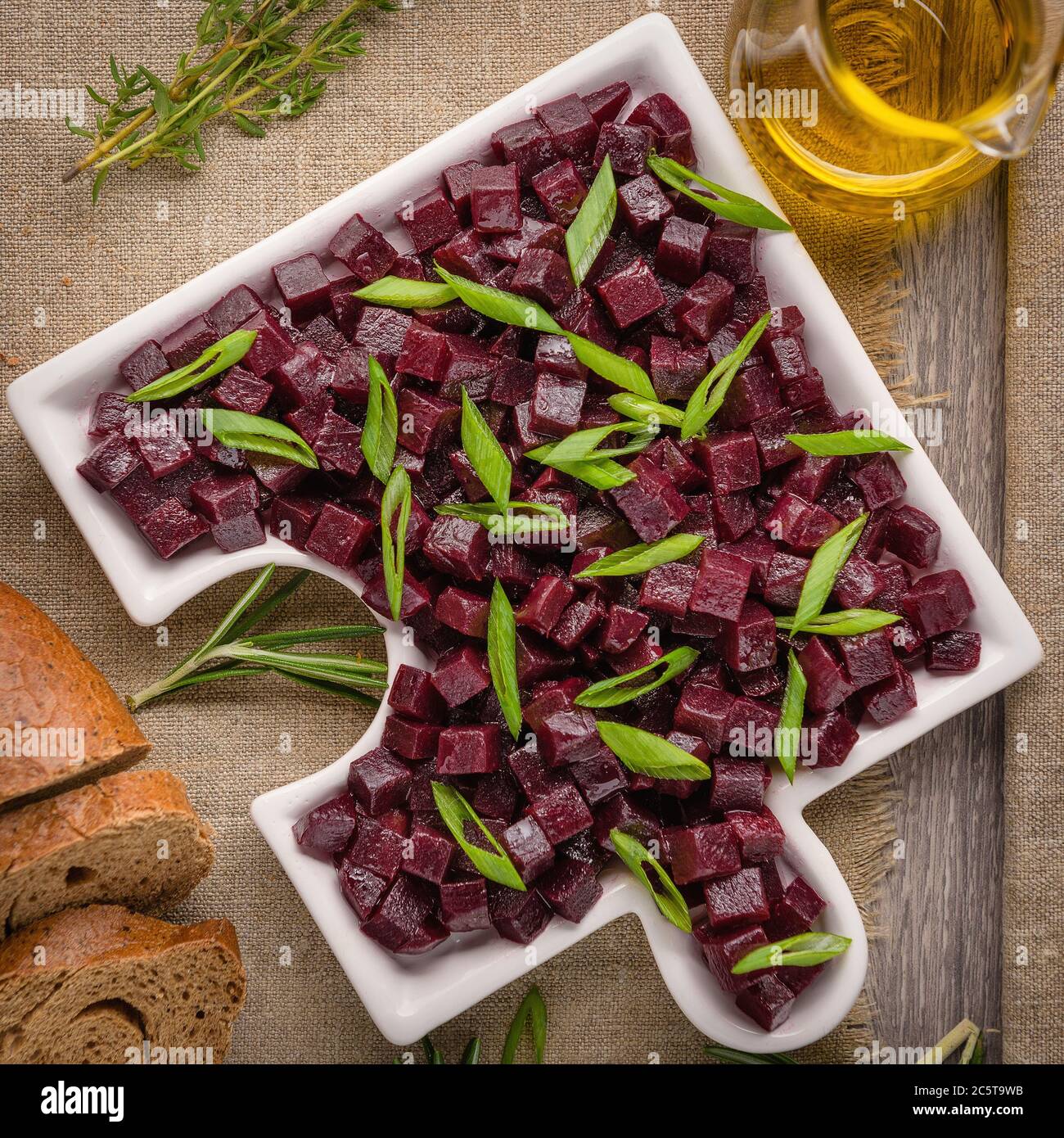 Delicious Fresh pieces of beet cube close-up with fresh onion and olive oil on a bag cloth on a rustic gray table. Beets are the root part of a beet p Stock Photo