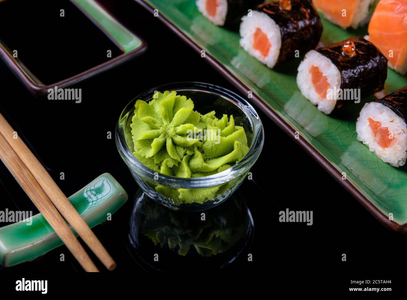 Japanese food. A set of various rolls of salmon, eel, shrimp and red caviar, in a beautiful green bowl, on a black background with reflection. Stock Photo