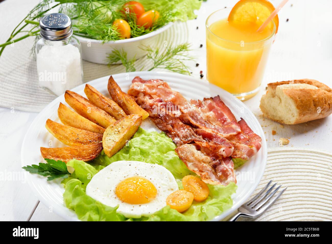 Morning breakfast with delicious fried bacon, French fries and tender egg, close-up. Stock Photo