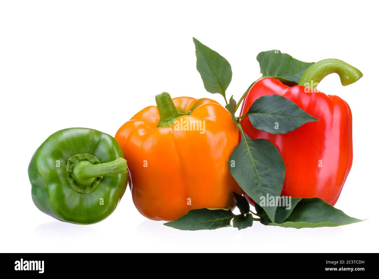 Fresh vegetables.Three sweet red, yellow, green peppers lying on green leaves, isolated on white background. Stock Photo