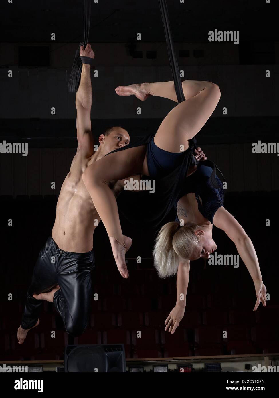 A sports acrobat couple performs a trick in the air. Acrobats on a dark ...