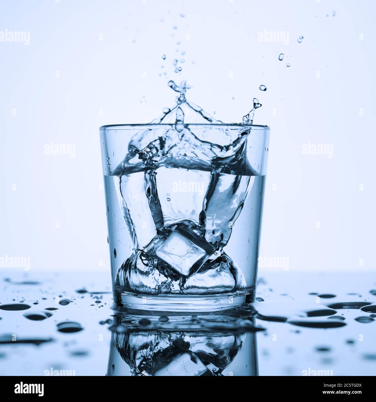 Splashes of clean water in a glass with ice, on a white background. Stock Photo