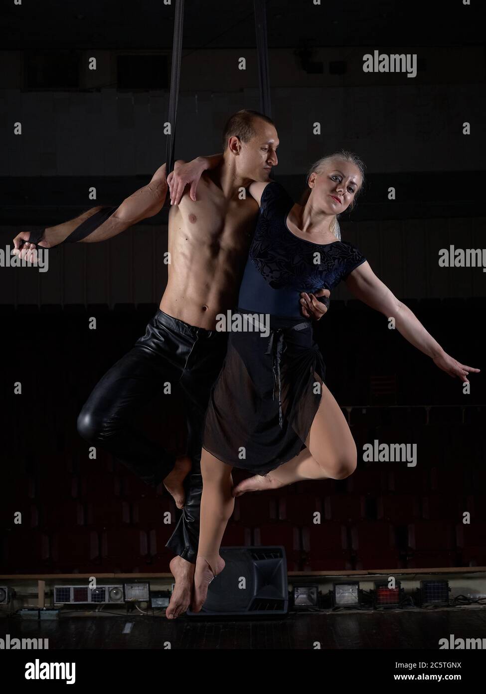 A sports acrobat couple performs a trick in the air. Acrobats on a dark ...