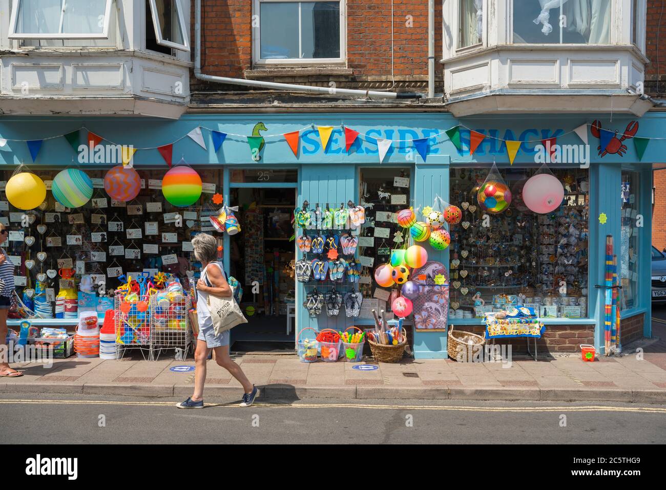Seaside shop UK, view of a mature woman walking past a colourful