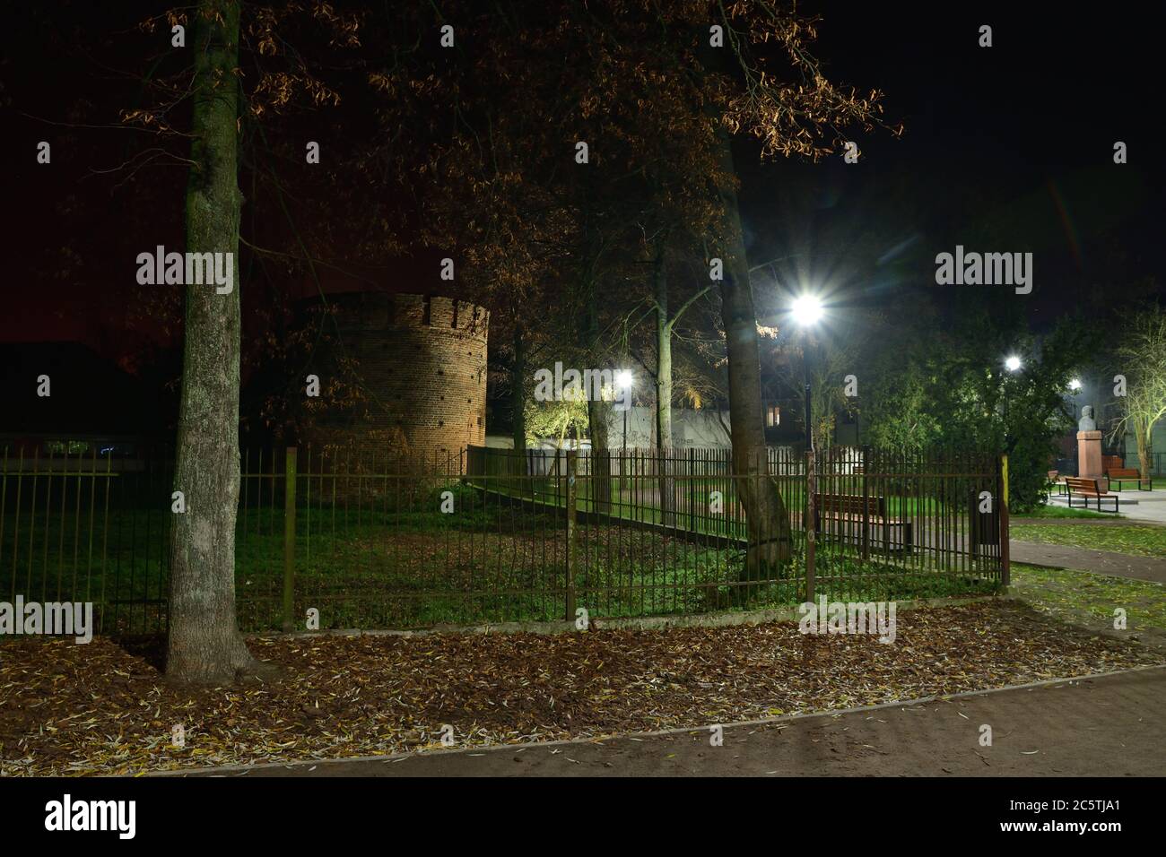 Pedestrian alley, benches and medieval tower at night illuminated with LED lamps. Summer. Stock Photo