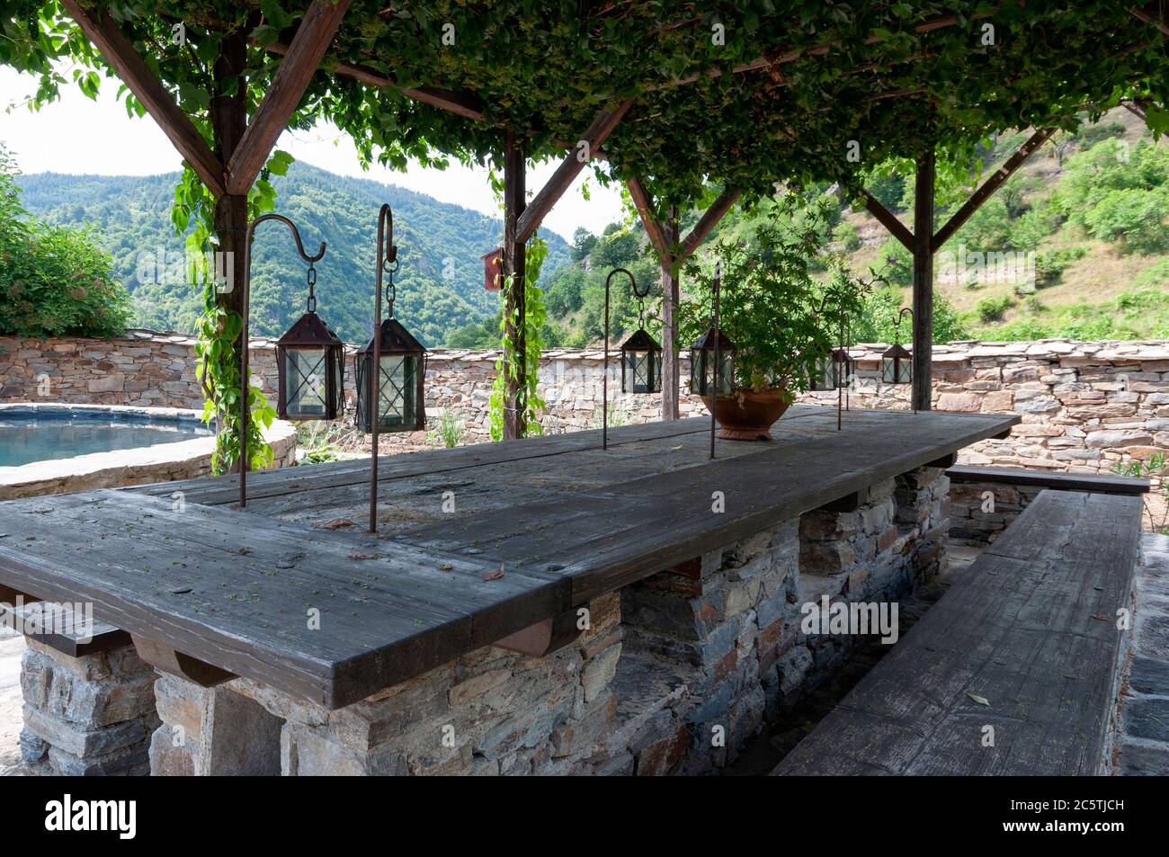 Dining and sitting area under pergola at romantic outdoor backyard space and unique patio of an old 19th century traditional Bulgarian timber house as an example of typical architecture style in the Rhodope Mountains on the Balkan Peninsula in Southeastern Europe Stock Photo