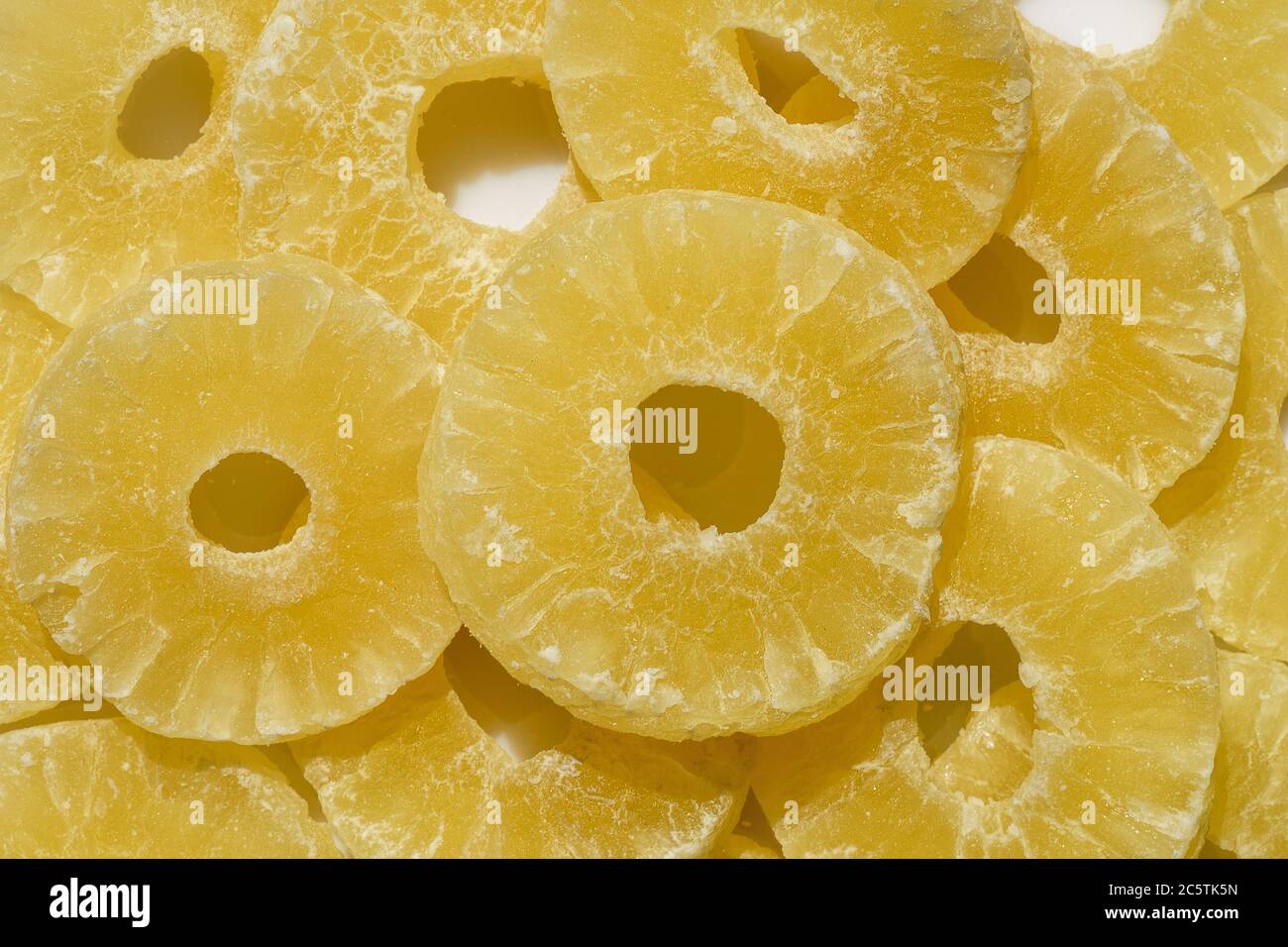 Yellow pineapple sweets cut in round slices in powdered sugar. Stock Photo