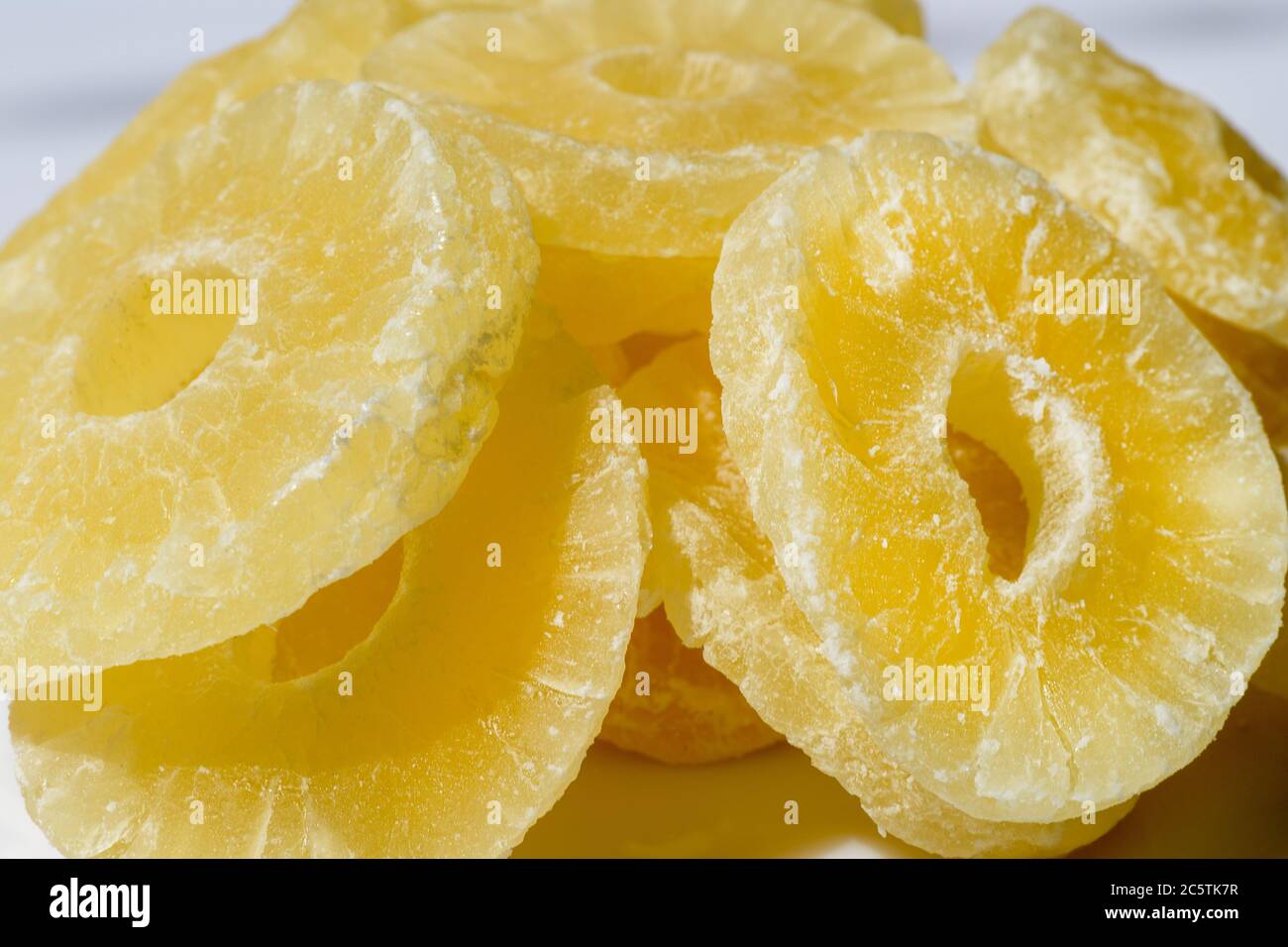 Dried pineapple candy rings, in powdered sugar, close-up. Stock Photo