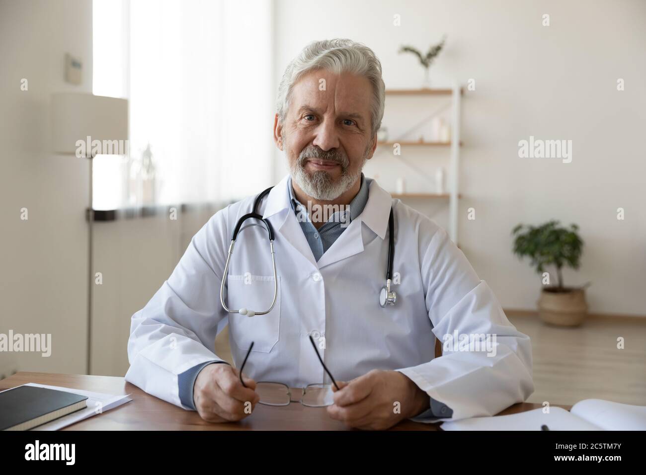 Portrait of smiling senior male doctor at workplace Stock Photo - Alamy