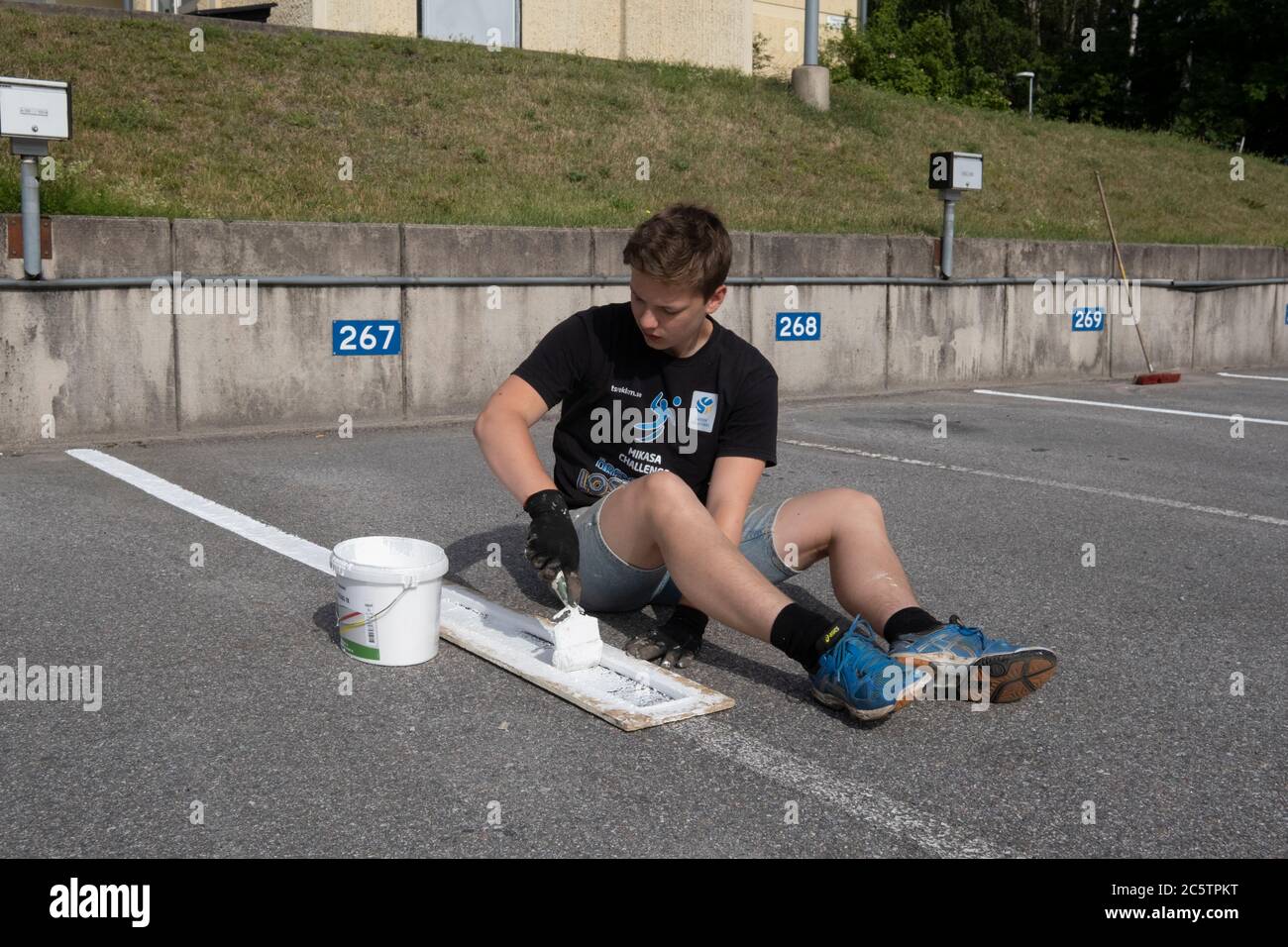 Young people have been given summer jobs to paint parking lines. Stock Photo