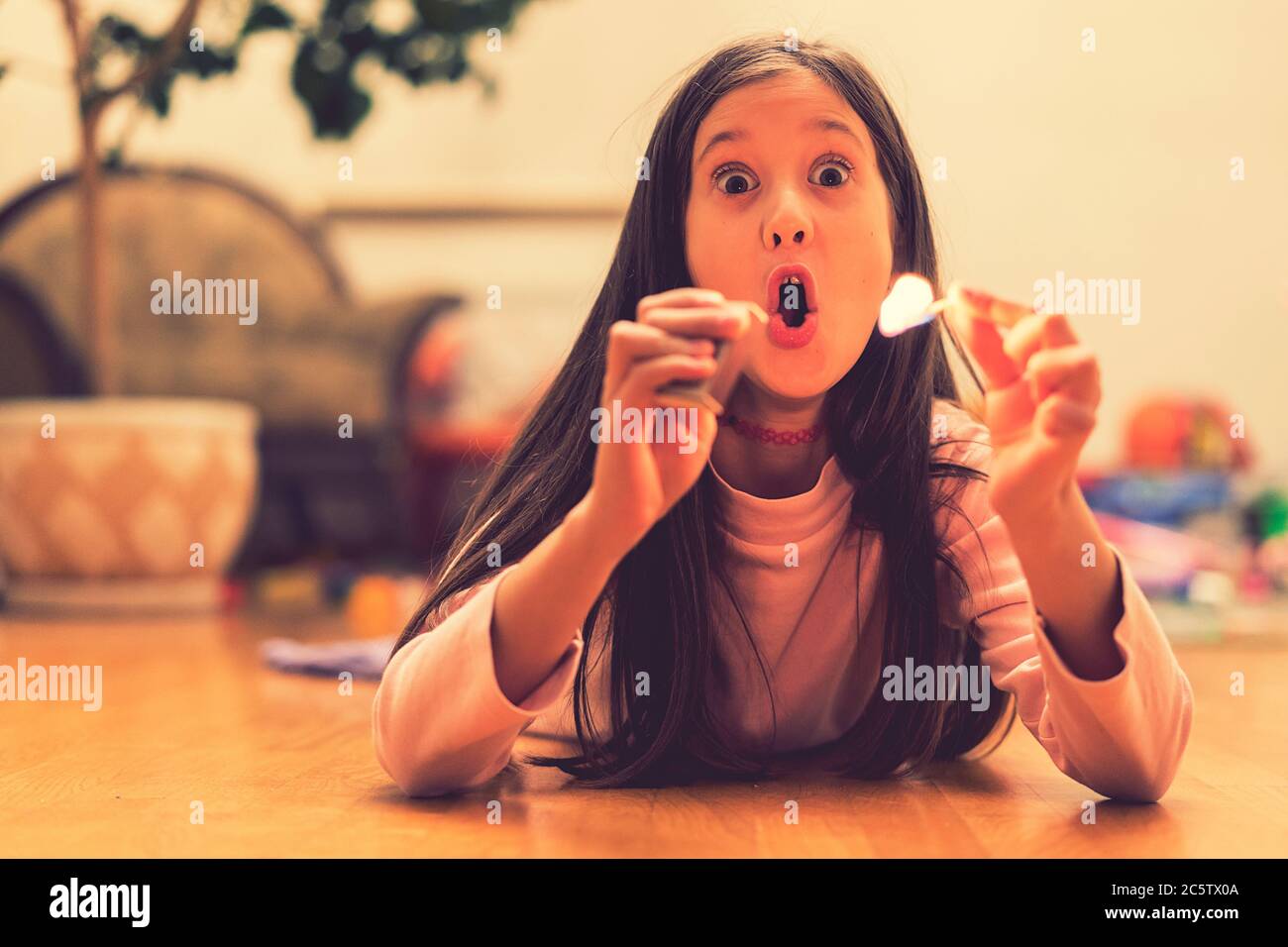 Girl playing with matches. Dangerous situation at home. A small child