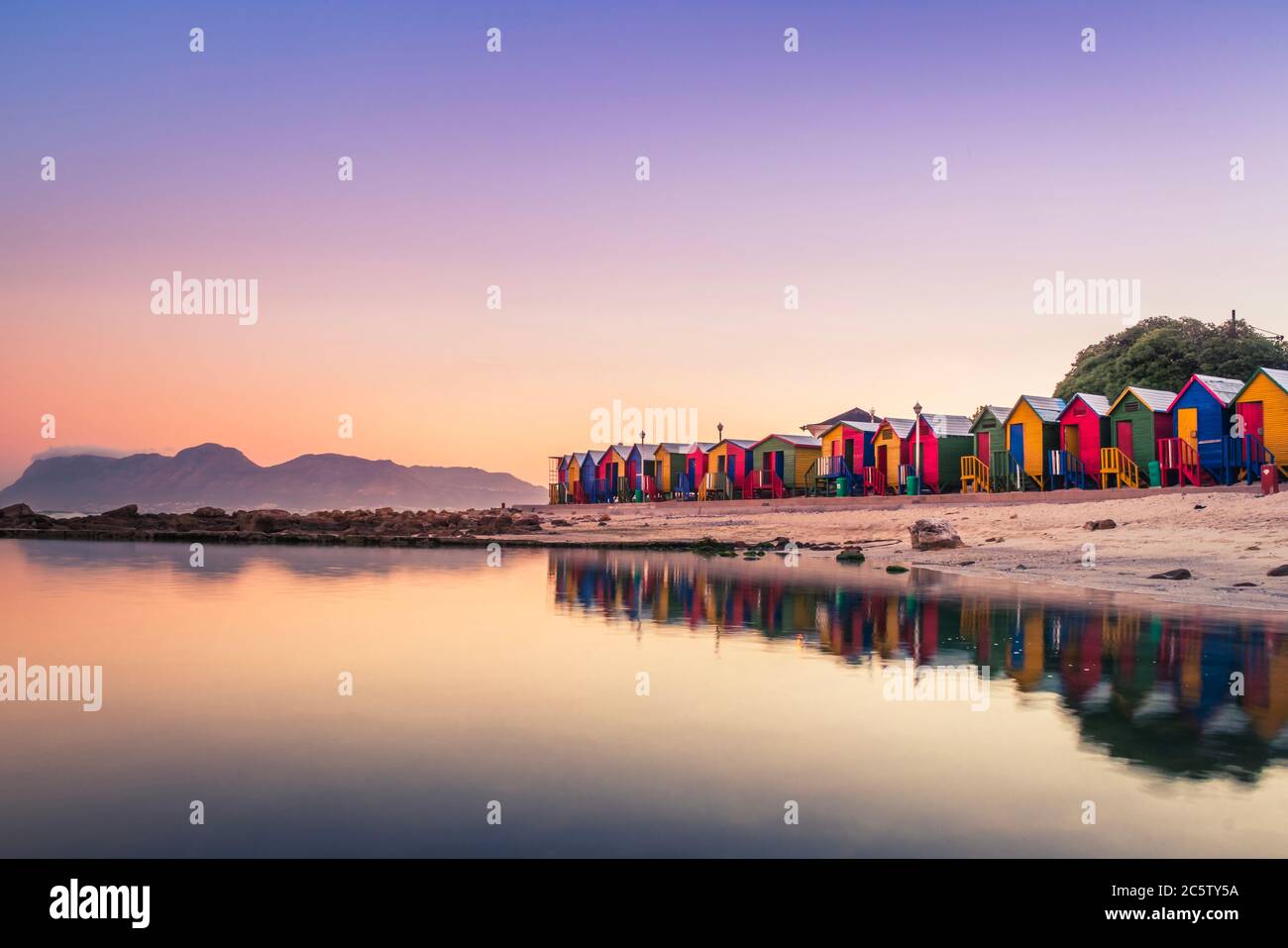 View of the beautiful sunset over False Bay from Kalkbay with little coloured houses on the beach, with mountains in the background, Cape Town, South Stock Photo