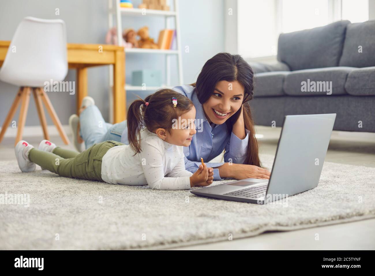 Happy mother and her cute little daughter watching online entertainment video together on laptop at home Stock Photo