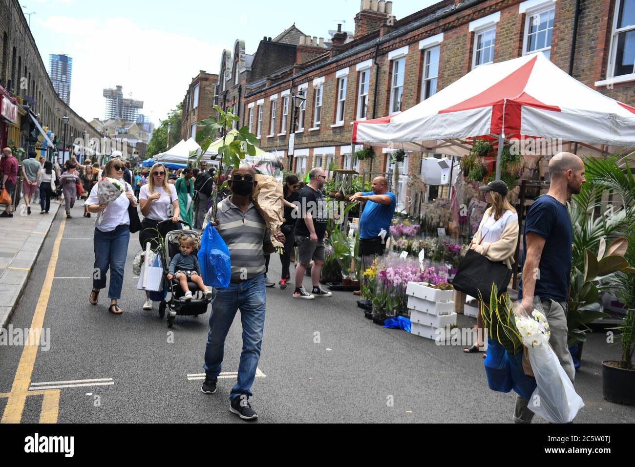 People visit Columbia Road Flower Market, London, as it reopens following the easing of coronavirus lockdown restrictions across England. Stock Photo